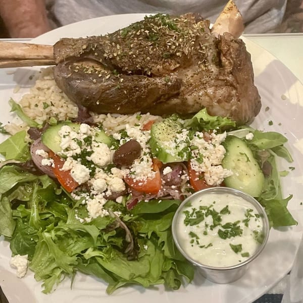 Athena Gyro's lamb shank with rice, Greek salad, and a side of tzatziki sauce.