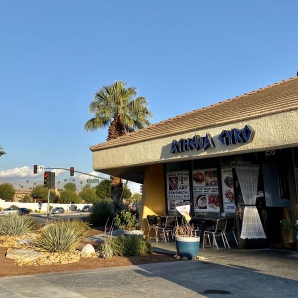 Exterior of Athena Gyro restaurant with a palm tree, desert landscaping, and street view.