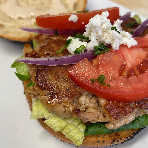 Athena Gyro's chicken sandwich with lettuce, red onion, tomato, and feta cheese on a bun.